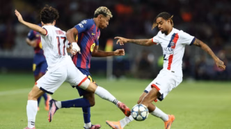 Lamine Yamal disputa bola com Vitinha e Bradley Barcola em jogo de Barcelona e PSG pela Champions League.