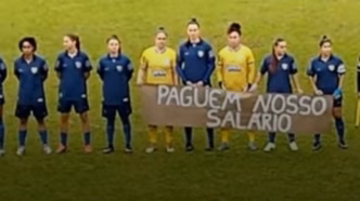 Jogadoras do Avaí Kindermann protestam com faixa por salários atrasados antes da semifinal do Campeonato Catarinense Feminino.