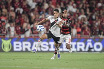 Oliveira, zagueiro do Vasco, em ação em partida contra o Flamengo, com foco em Bruno Henrique.