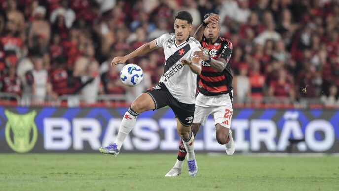 Oliveira, zagueiro do Vasco, em ação em partida contra o Flamengo, com foco em Bruno Henrique.