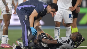 Kaio Pantaleão, zagueiro do Botafogo, em campo recebendo atendimento médico após sofrer lesão no joelho.
