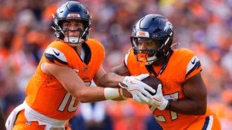 Jogadores do Denver Broncos em campo durante um jogo da NFL, com foco na ação.
