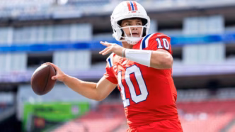 Drake Maye lançando um passe longo durante um jogo da NFL.