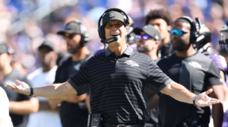 Treinador John Harbaugh dos Baltimore Ravens em campo.