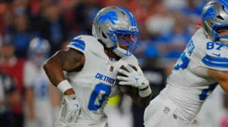 Jahmyr Gibbs correndo com a bola em campo durante um jogo da NFL.