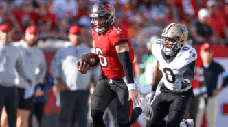 Campo do Superdome com jogadores em ação durante partida da NFL entre Buccaneers e Saints.