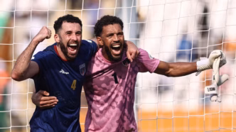 Goleiro Vozinha de Cabo Verde celebra um gol com o zagueiro Roberto Lopes. Ambos demonstram alegria em campo.